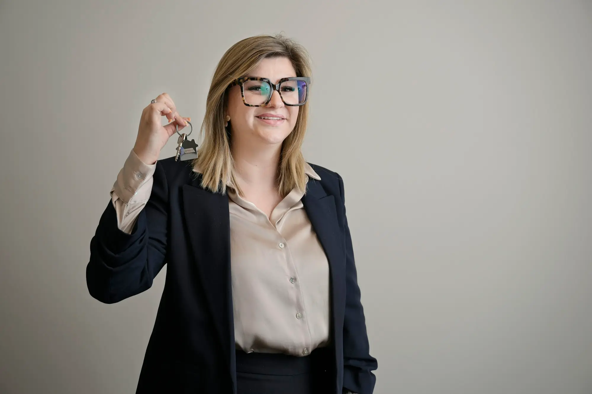 Smiling woman holding out a set of keys, ready to hand them over to a buyer