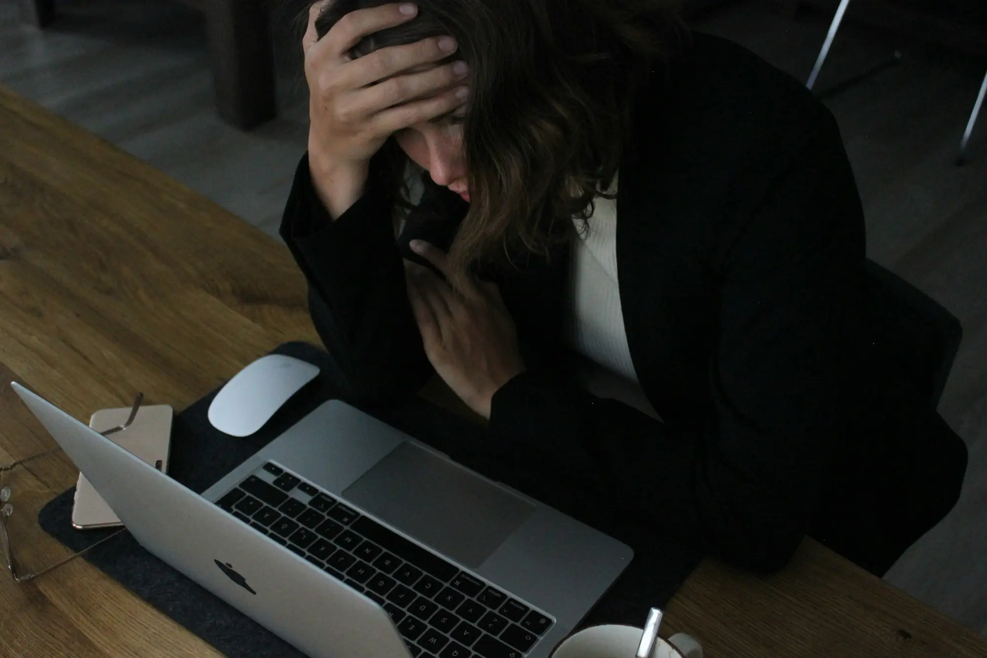 Stressed woman with her head in her hands while looking at bills on a laptop