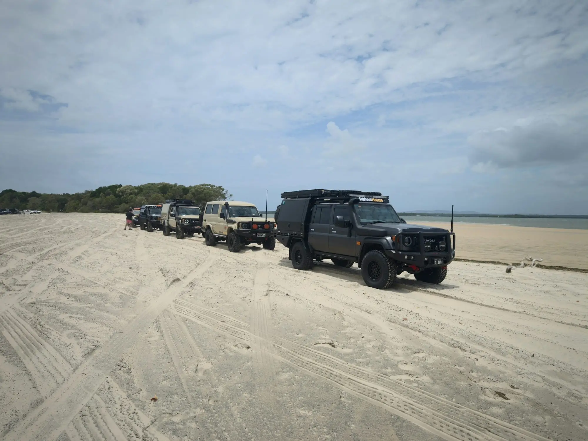 Convoy of 4WDs led by a LandCruiser 79 lined up on an Australian beach