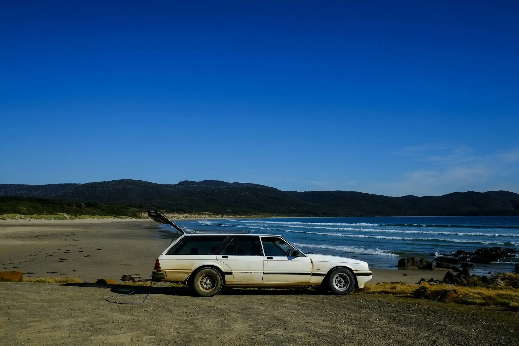 White Ford Falcon station wagon parked on a quiet Australian beach