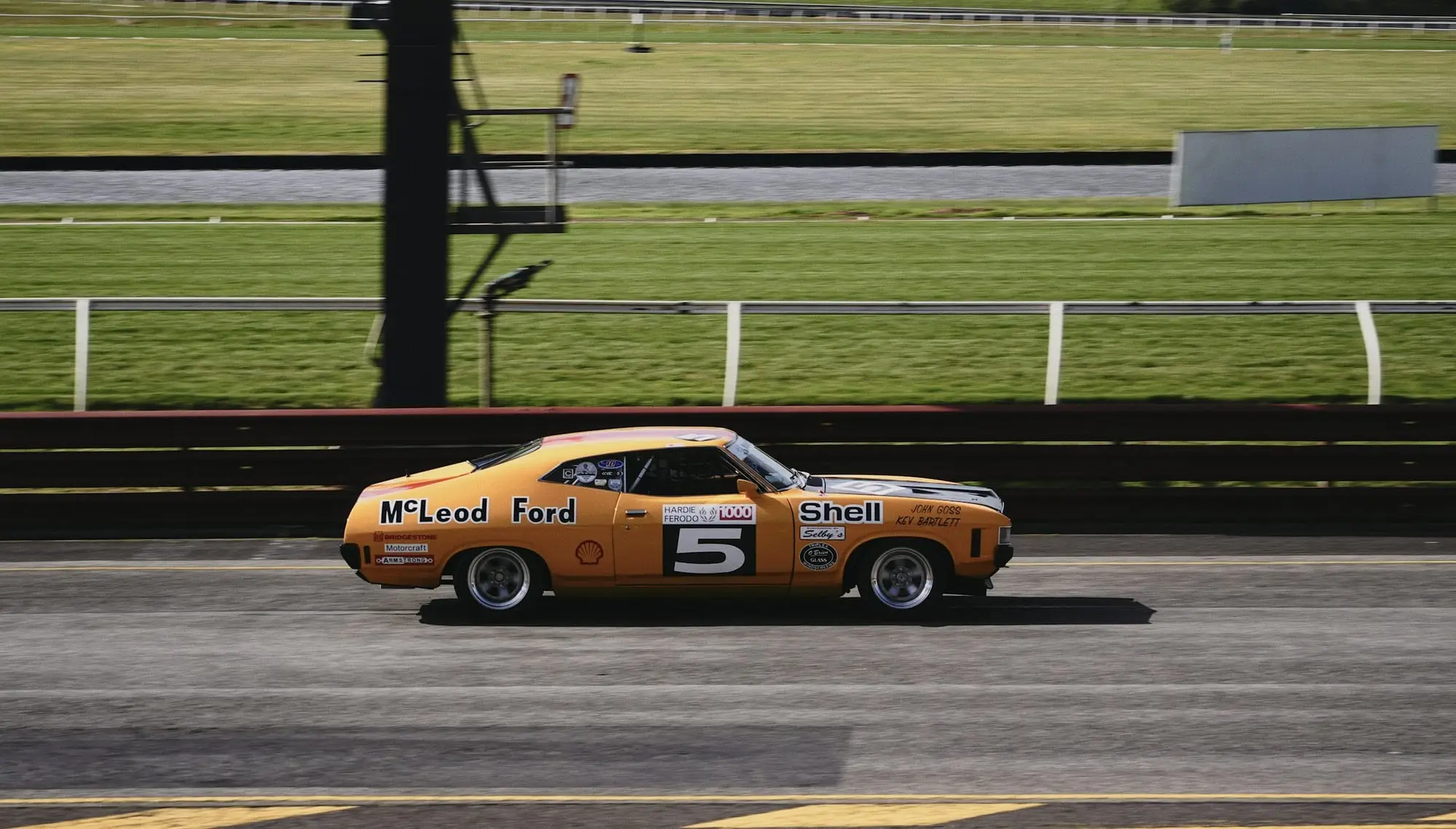 Orange Ford XB Falcon historic touring car number 5 racing along the main straight