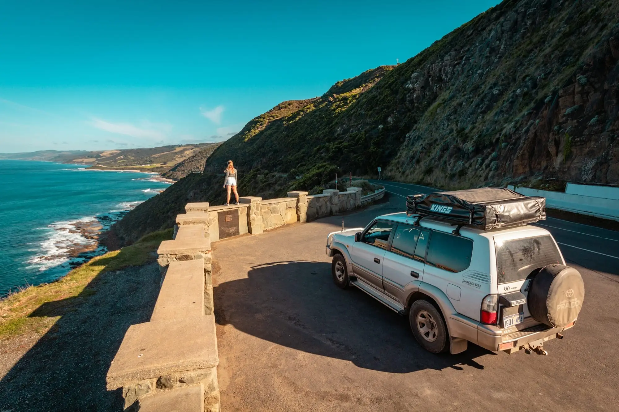 Toyota Prado with a rooftop tent stopped at a coastal lookout above the ocean