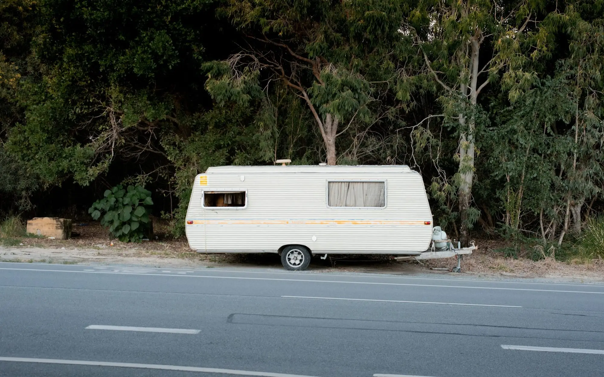 Vintage caravan parked on the roadside against thick Australian bush
