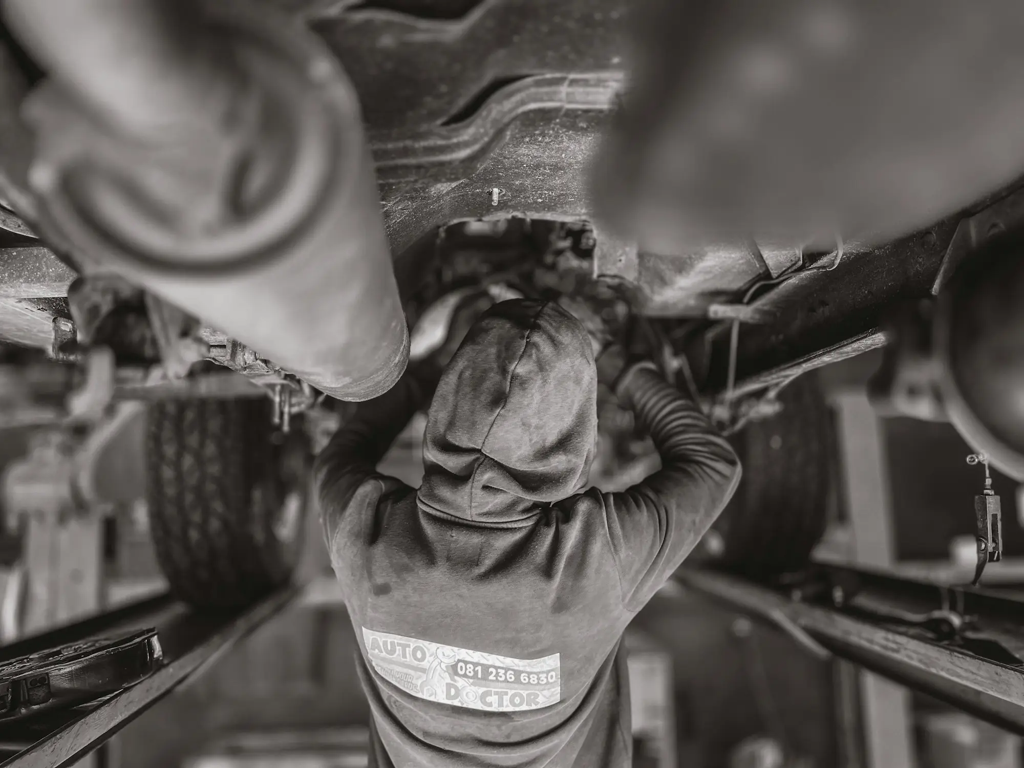 Black and white photo of a mechanic working on a car before a used car purchase
